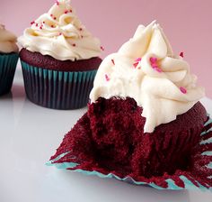 three cupcakes with white frosting and sprinkles on them sitting on a plate