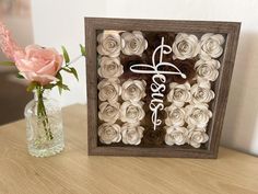 there is a vase with roses in it next to a framed sign that says love