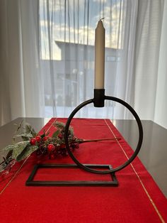 a candle sits on top of a red table cloth with a metal ring around it