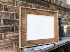 a wooden frame sitting on top of a brick wall next to a potted plant