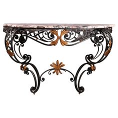 an ornate console table with marble top and wrought iron work on the base, against a white background