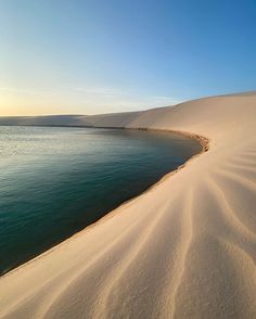 the sun is setting over a body of water in an area that looks like sand dunes