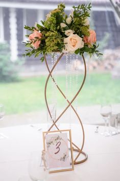 an elegant centerpiece with roses and greenery is displayed in front of a window