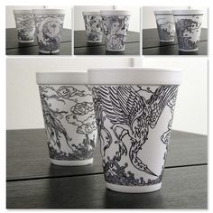 two cups sitting on top of a wooden table covered in black and white art nouveau designs