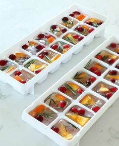 two ice trays filled with fruit and veggies on top of a table