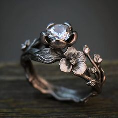 a close up view of a ring with flowers on the side and a diamond in the middle