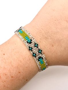 Green and Clear Pattern Seed Bead Bracelet delicately handmade by an indigenous Mayan family of women in Guatemala. This neutral-colored bracelet is a must have for a his and hers every day accessory! Makes for a great birthday gift, Christmas gift, holiday gift, stocking stuffer, friendship bracelet and a his/hers, his/his, hers/hers couples bracelet! *Please note that all of our items are handcrafted and unique to each piece. Also, colors may vary slightly based on your device. Like what you s Artisan Adjustable Silver Bead Bracelets, Artisan Silver Beads Adjustable Bracelets, Artisan Silver Beads Adjustable Bracelet, Bohemian Friendship Bracelets With Silver Beads, Bohemian Silver Beads Friendship Bracelets As Gift, Bohemian Silver Friendship Bracelets With Tiny Beads, Silver Bracelet With Tiny Beads For Festivals, Artisan Adjustable Beaded Bracelets With Silver Beads, Adjustable Southwestern Bracelets As Gift