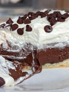 a piece of cake with chocolate chips on top and whipped cream on the bottom, sitting on a plate