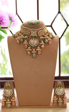 an elaborate necklace and matching earrings on display in front of a vase with purple flowers