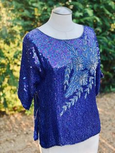 This is a vibrant blue floral sequin top blouse that is perfect with Jeans or a dressed up pant. The fabric is pure silk with sequin embellishment. This lovely top is made in India by Jasmine by K.V.M. Calif.  Measurements laying flat across: Pit to pit-22" Waist- 20" Length- 22.5" Sleeves- 13" Festive Embellished Blue Blouse, Festive Blue Embellished Blouse, Blue Fitted Silk Tops, Fitted Silk Blue Tops, Fitted Blue Silk Tops, Festive Blue Evening Blouse, Festive Evening Blue Blouse, Blue Fitted Blouse For Evening, Blue Sequin Fabric For Summer Night Out