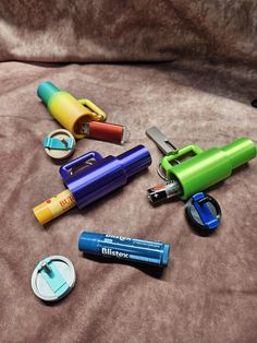 several different types of lighters and batteries on a bed with a brown blanket behind them