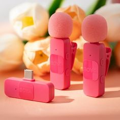 two small pink objects sitting next to each other on a table with flowers in the background