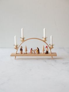 a nativity scene with candles and figurines on a wooden stand in front of a white wall