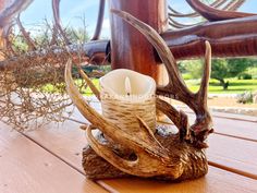 an antler's head with a candle in it sitting on a wooden table