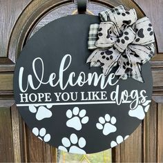 a welcome sign hanging on the front door of a house with dog paws painted on it