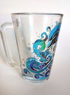 a glass mug with blue swirls and bubbles on the inside is sitting on a white surface