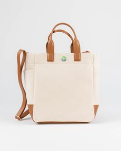 The Cape Code Tote is a truly elevated and refined take on the classic design. The design featured dual handles and a detachable strap for convenience. The spacious interior will fit all your daily needs and even works as a weekender or picnic bag. The streamlined style complements any outfit and works for his, hers, and theirs. • Natural/Saddle • 100% cotton with leather trim • Unlined • Two exterior side pockets • Leather bottom • Detachable & adjustable strap • 6” handle drop • Measures 11.5” Travel Weekender Bag With Coated Canvas Handles, Beige Weekender Bag For On-the-go, Everyday Canvas Travel Bag With Top Carry Handle, Everyday Canvas Travel Bag With Top Handle, Modern Travel Bag With Handles For On-the-go, Beige Top Handle Weekender Bag, Canvas Travel Bag With Top Carry Handle, Beige Travel Bag With Handles For Everyday Use, Beige Travel Bag For Everyday Use