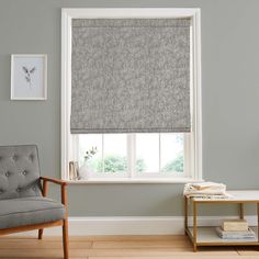 a living room with gray walls and a window covered in roman shades that match the curtains