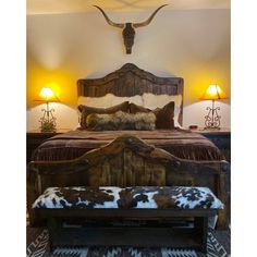 a bed with a cow head on the wall above it and two lamps next to it