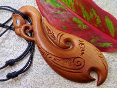 a wooden brooch sitting on top of a table next to a green and red leaf