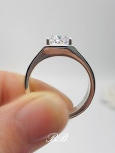 a hand holding a ring with a diamond in it