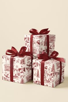 three presents wrapped in red and white wrapping paper with bows on them, sitting next to each other