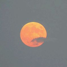 an orange moon is seen through the clouds