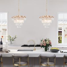 a white kitchen with gold accents and chandeliers