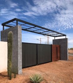 a house with a cactus in front of it and a metal fence around the entrance