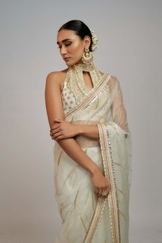 Editor's Note Radiate timeless beauty in this beautiful organza sari set, where subalpine detailing paired with a halter neck blouse creating a captivating look for special occasions. The blend of traditional craftsmanship and modern sensibilities makes it a must-have for those seeking a perfect balance between traditional yet evergreen style. Wedding Blouse With Sheer Dupatta For Diwali, Designer Wear Organza Blouse Piece For Transitional Season, Traditional Organza Blouse For Festive Occasions, Transitional Organza Blouse Piece For Designer Wear, Festive Organza Blouse Piece For Transitional Season, Festive Transitional Organza Blouse Piece, Designer Cutdana Organza Blouse, Designer Organza Blouse With Cutdana, Wedding Blouse With Sheer Dupatta For Eid