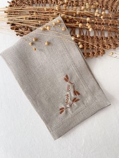 two linen napkins with embroidered leaves on them