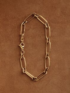 In our quest for the perfect chain—one that could be handcrafted and worn daily, with timeless elegance—we designed and made the Long & Short Chain. Featuring a traditional pattern of elongated, paperclip-style links joined by smaller ovals, this chain lays flat against the arm or chest in a seamless arrangement. Each link is carefully shaped, assembled, and fully soldered by hand in our Burlington studio. The chain is secured with a subtly adorned lobster clasp, designed for durability. On the Timeless Gold Chain Bracelet, Classic Link Chain Bracelet With Cable Chain, Classic Figaro Chain Bracelet With Oval Links, Formal Chain Link Bracelet With Hook And Links, Classic Link Cable Chain Bracelet, Classic Cable Link Chain Bracelet, Classic Oval Link Chain Bracelets, Timeless Chain Link Bracelet, Elegant Metal Chain Bracelet With Hooks And Links