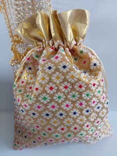 a bag that has some beads hanging from it's side and is decorated with gold ribbon