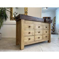 a large wooden dresser sitting on top of a tiled floor next to a potted plant