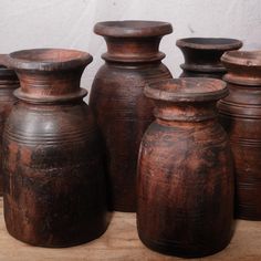 several brown vases sitting on top of a wooden table