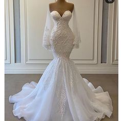 a white wedding dress on display in front of a mannequin headdress