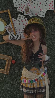 a woman wearing a skirt and hat standing next to playing cards on the ground in front of a mirror