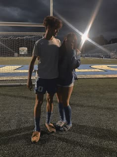 two people standing on a soccer field at night