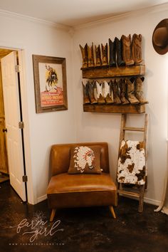 a brown chair sitting in front of a wooden shelf filled with cowboy hats and boots