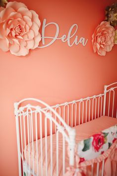 a baby crib with pink flowers on the wall