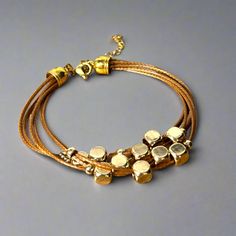 Get ready to elevate your wrist game with this multi-strand leather bracelet. Featuring gold-plated floating beads and a lobster clasp closure, this timeless piece is the perfect way to add a touch of sophistication to any outfit. Length: 6.5" + 1.5" extender chain Lobster clasp closure - for a secure fit 6 strands of brown leather - for the perfect boho vibe 18K PVD Gold plated stainless steel - long lasting plating and hypoallergenic Handmade in China - to bring you the best possible price Thi Adjustable Gold Leather Bracelet Chic Style, Adjustable Everyday Jewelry With Gold Clasp, Adjustable Gold Leather Chic Bracelet, Gold Adjustable Double Strand Beaded Bracelets, Adjustable Gold Bracelets For Accessorizing, Modern Multi-strand Gold Jewelry, Modern Gold Multi-strand Jewelry, Adjustable Gold Leather Bracelet, Adjustable Gold Beaded Metal Bracelets