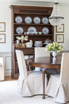 a dining room table and chairs with plates on the wall behind it, in front of a china cabinet