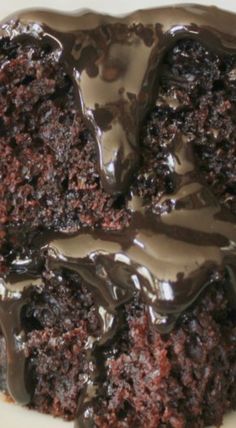 a close up of a piece of chocolate cake on a white plate with frosting