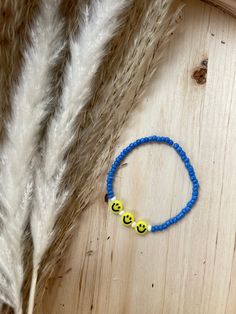 a bracelet with two smiley faces on it sitting next to some white fur and feathers