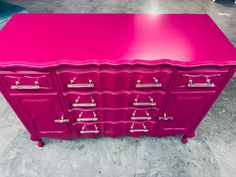 a pink dresser with many drawers and handles