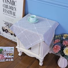 a table with a cup and saucer sitting on top of it next to flowers