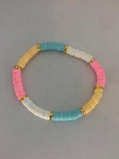 a bracelet with two different colored beads and gold plated clasps on a gray background