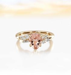 an engagement ring with a pink morganite and white diamonds on the side, set in yellow gold