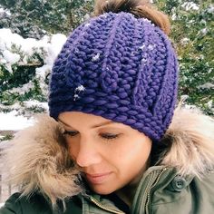 a woman wearing a purple knitted beanie and looking down at her cell phone