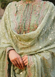 The kameez and Sharara Mint Green Pakistani Wedding Dress is a stunning attire adorned with sequins, beads, and floral designs. Perfect stitching, lavish designs, and hand-crafted embellishments make this stunning Pakistani dress an epitome of beauty and grace. Pakistani Kameez: The Kameez has an alluring mint green shade and is emblazoned with luxury designs, embroidery, and shimmering ornaments. Sequins and beads give a glamorous touch to this perfectly stitched kameez in premium chiffon fabri Embellished Green Chanderi Anarkali Set, Embellished Pista Green Anarkali Set For Eid, Eid Embellished Pista Green Kurta, Eid Embellished Pista Green Lehenga, Pista Green Embellished Kurta For Festive Occasions, Festive Embellished Pista Green Kurta, Unstitched Embellished Green Sharara, Green Embellished Unstitched Sharara, Unstitched Green Embellished Anarkali Set